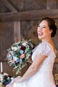 bride laughing while holding sola wood bouquet at her barn wedding in Massachusetts
