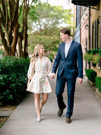 A documentary style wedding photography shot of a couple walking past historic Charleston architecture, showcasing a refined composition.
