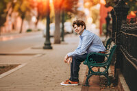 High school senior sitting on a bench in downtown New Bern during a senior portrait session