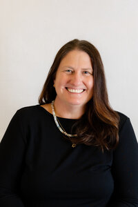 Woman smiling and wearing black and sitting for a professional headshot in the Bay Area