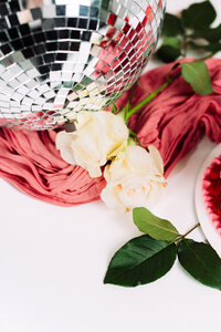 Styled detail with a disco ball, flowers, pink fabric, and cake from business brand photoshoot.
