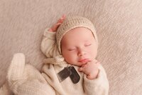Army dad holding newborn baby close in soft neutral family portrait