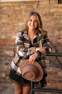 A girl from Catholic Memorial High school leans against an iron railing in front of a brick wall in Milwaukee's Third Ward for her senior picture.