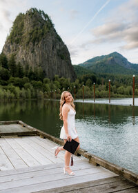 Girl getting her cap and gown portraits done at Beacon Rock State Park on the dock.