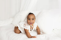Baby girl wearing white dress and bonnet during mommy and me photoshoot in Franklin Tennessee photography studio