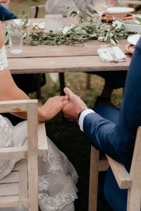 Bride and groom hold hands under table