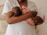 In-home lifestyle photo of mother holding newborn