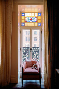 Bridal heels placed on a chair in front of stained glass windows at Hotel Chelsea in New York City, photographed during Japna and Chris’s intimate elopement by NYC wedding photographer Perry Hancock.