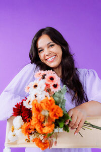Singer-songwriter holding a colorful bouquet against a purple backdrop for musician branding