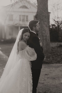 black and white image of bride embracing groom from behind