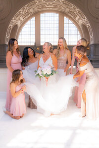san francisco city hall bride with bridesmaids fluffing dress