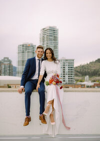 couple sitting on a ledge kelowna rooftop elopement