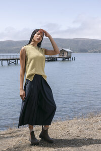 Full-length editorial frame of a chartreuse knit tank and navy midi skirt against the bay
