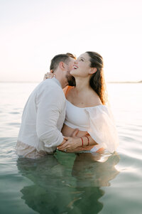Expecting parents laughing together in the sea, lifestyle maternity photographer