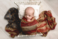 Baby boy sleeping draped in an American Flag scarf during his newborn session near Mankato, Minnesota.