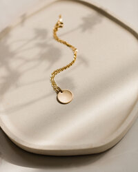 Lifestyle product photography of a gold gorjana necklace styled on a neutral stone surface, photographed for a jewelry brand campaign by San Diego commercial photographer Chelsea Loren.
