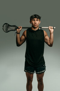 A young man from Catholic Memorial High School poses for his senior portraits with his Lacrosse equipment in our Waukesha studio.