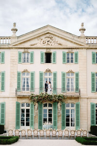 A wide, refined composition of a couple on a chateau balcony, highlighting the intentional imagery of a multi-day wedding celebration at Chateau de Tourreau.