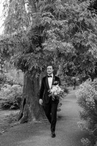Groom wearing black tux and holding bridal bouquet