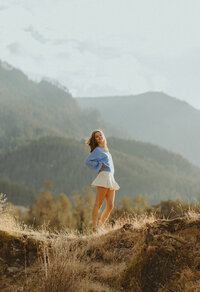 girl standing in field in front of mountainside view
