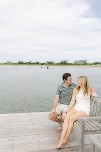 Couple laugh as they sit on dock at The Wauwinet, Nantucket.