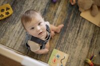 A baby plays in the play yard in the living room.