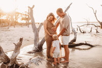 Folly Beach Maternity Photographer -- Pregnant woman poses for Maternity Photos at the Lighthouse Inlet Heritage Preserve on Folly Beach with iconic views of the Morris Island Lighthouse in the distance.