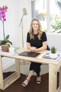 Female entrepreneur sitting at a desk during a Ventura County brand photography session.