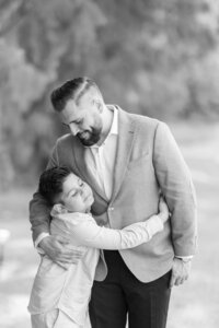 Black and white portrait of the Dilorio family father embracing his son during a heartfelt outdoor family photography session in Las Vegas.
