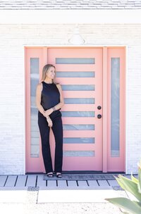 Entrepreneur standing at a modern pink door during a Ventura County brand photography session.