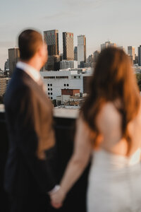 Mariés de dos admirant le skyline de Montréal, photo en flou artistique, moment contemplatif sur la terrasse de l'Hôtel St-Thomas