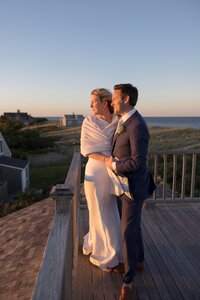 Bride and Groom stand on rooftop of Nantucket home with Atlantic Ocean behind them.