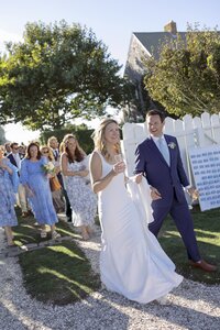 Bride and Groom walk hand in hand to their outdoor cocktail reception on Nantucket.