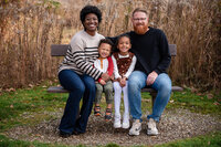 Family sitting together on a bench outdoors during a Cleveland family photography session