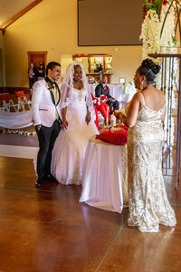 Venice Beach Los Angeles wedding photography of the bride and groom during the ceremony receiving a meaningful gift from the mother of the groom, captured in a candid documentary moment with true to life color.