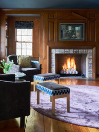 Library with wood paneling, round silk rug, gas fireplace, lounge chairs
