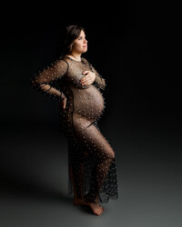 Fine art maternity portrait of a pregnant woman in a sheer pearl maternity gown in a studio session by Kaitlyn Dawn Photography.