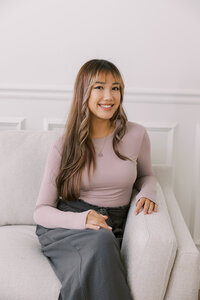 Woman sitting on a loveseat at The Bunny Hive and smiling