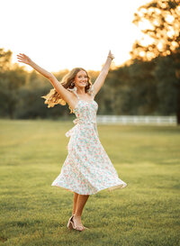 Senior portrait in downtown Magnolia Springs, Alabama — celebrating with her arms raised in the air.