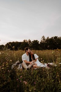 Couple sitting together in a field of wildflowers.