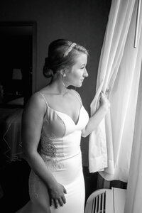 Black and white photo of a bride at a hotel window in Downtown Los Angeles with soft natural light