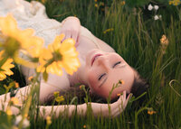 Girl laying in the grass with sunflowers with her for her senior portraits in the Columbia River Gorge.