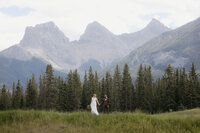 Man and wife standing in front of the famous three sisters mountains in Canmore