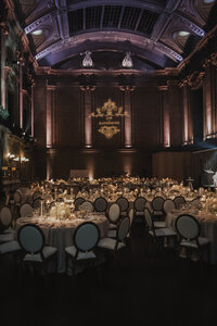 Salle de réception grandiose au Théâtre St-James à Montréal, tables rondes aux chandelles, monogramme des mariés projeté au mur, chaises médaillon élégantes