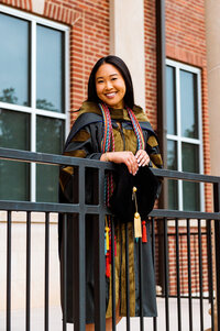 Lipscomb University Master's degree attire senior girl smiling at camera leaning on the banister