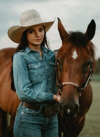 Senior portrait at Triple T Farms in Fruitdale, Alabama — standing beside her brown horse,
holding the reins.