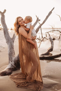 Folly Beach Maternity Photographer -- Pregnant woman poses for Maternity Photos at the Lighthouse Inlet Heritage Preserve on Folly Beach with iconic views of the Morris Island Lighthouse in the distance.