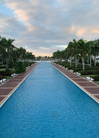 Main Pool at Hard Rock Punta Cana facing the ocean at dusk. Large energetic family friendly resort in Punta Cana that is perfect for a group getaway or destination wedding