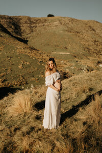 Pregnant woman standing through tall grass during a maternity session in Banks Peninsula