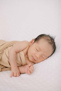 newborn baby boy wrapped in a neutral-colored swaddle